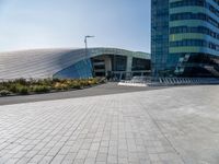 the woman is riding her bike near the building and her reflection on the mirroring glass of the side