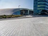 the woman is riding her bike near the building and her reflection on the mirroring glass of the side