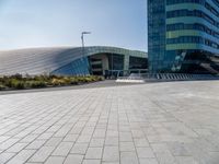 the woman is riding her bike near the building and her reflection on the mirroring glass of the side