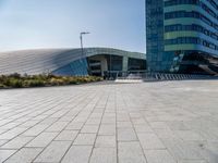 the woman is riding her bike near the building and her reflection on the mirroring glass of the side