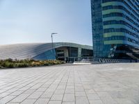 the woman is riding her bike near the building and her reflection on the mirroring glass of the side