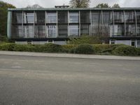 a woman riding on the back of a red bike next to a building and hedges