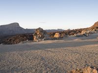 a woman riding a horse through the middle of a desert desert near mountains of rock formations