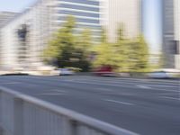 a woman rides a motorcycle in a motion on the side of the street with tall buildings