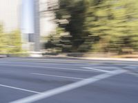 a woman rides a motorcycle in a motion on the side of the street with tall buildings