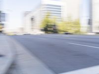 a woman rides a motorcycle in a motion on the side of the street with tall buildings