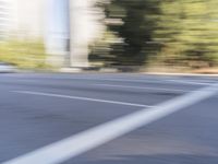 a woman rides a motorcycle in a motion on the side of the street with tall buildings