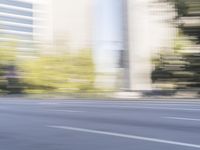 a woman rides a motorcycle in a motion on the side of the street with tall buildings