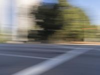 a woman rides a motorcycle in a motion on the side of the street with tall buildings