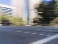 a woman rides a motorcycle in a motion on the side of the street with tall buildings