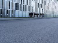 a woman in black shirt riding a skateboard down a city street corner in front of large tall buildings