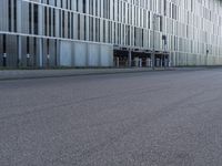a woman in black shirt riding a skateboard down a city street corner in front of large tall buildings
