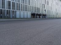 a woman in black shirt riding a skateboard down a city street corner in front of large tall buildings