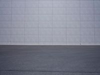 a woman is riding a skateboard on an empty parking lot next to the wall