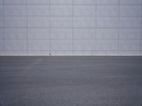a woman is riding a skateboard on an empty parking lot next to the wall