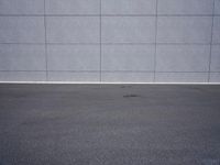 a woman is riding a skateboard on an empty parking lot next to the wall