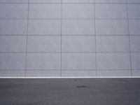 a woman is riding a skateboard on an empty parking lot next to the wall