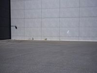 a woman is riding a skateboard on an empty parking lot next to the wall