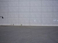 a woman is riding a skateboard on an empty parking lot next to the wall