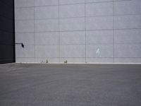 a woman is riding a skateboard on an empty parking lot next to the wall