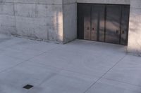 a woman riding a skateboard on top of a sidewalk next to two doors of an office