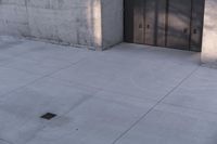 a woman riding a skateboard on top of a sidewalk next to two doors of an office