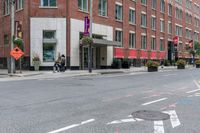 a woman rides a skateboard down the street in front of the red brick building