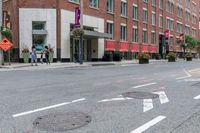 a woman rides a skateboard down the street in front of the red brick building