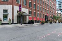 a woman rides a skateboard down the street in front of the red brick building