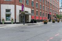 a woman rides a skateboard down the street in front of the red brick building