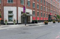 a woman rides a skateboard down the street in front of the red brick building