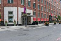 a woman rides a skateboard down the street in front of the red brick building