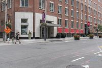 a woman rides a skateboard down the street in front of the red brick building