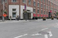 a woman rides a skateboard down the street in front of the red brick building