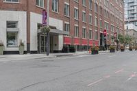 a woman rides a skateboard down the street in front of the red brick building