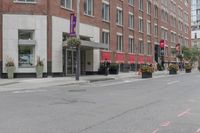 a woman rides a skateboard down the street in front of the red brick building