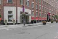 a woman rides a skateboard down the street in front of the red brick building