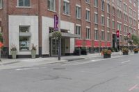 a woman rides a skateboard down the street in front of the red brick building