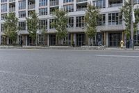 a woman is riding a skateboard down the sidewalk in front of a building with lots of windows