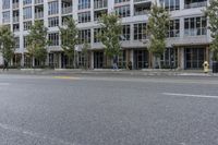 a woman is riding a skateboard down the sidewalk in front of a building with lots of windows