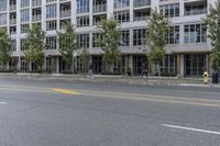 a woman is riding a skateboard down the sidewalk in front of a building with lots of windows