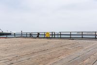 the wooden floor of a pier with a yellow surf board in the water behind it