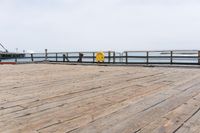 the wooden floor of a pier with a yellow surf board in the water behind it