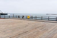 the wooden floor of a pier with a yellow surf board in the water behind it