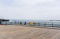 the wooden floor of a pier with a yellow surf board in the water behind it