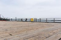 the wooden floor of a pier with a yellow surf board in the water behind it