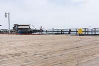 the wooden floor of a pier with a yellow surf board in the water behind it