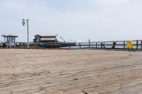 the wooden floor of a pier with a yellow surf board in the water behind it