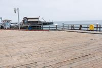 the wooden floor of a pier with a yellow surf board in the water behind it