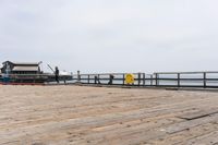 the wooden floor of a pier with a yellow surf board in the water behind it